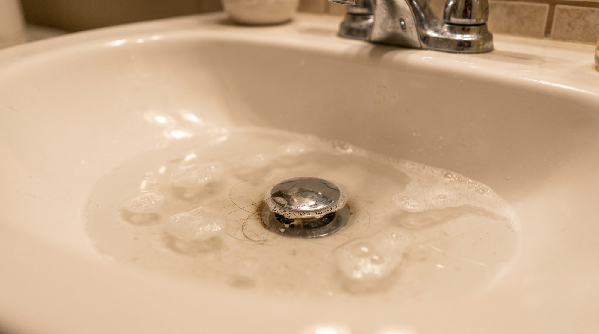 Valley Plumbing technician clearing a clogged bathroom sink drain at a Utah home