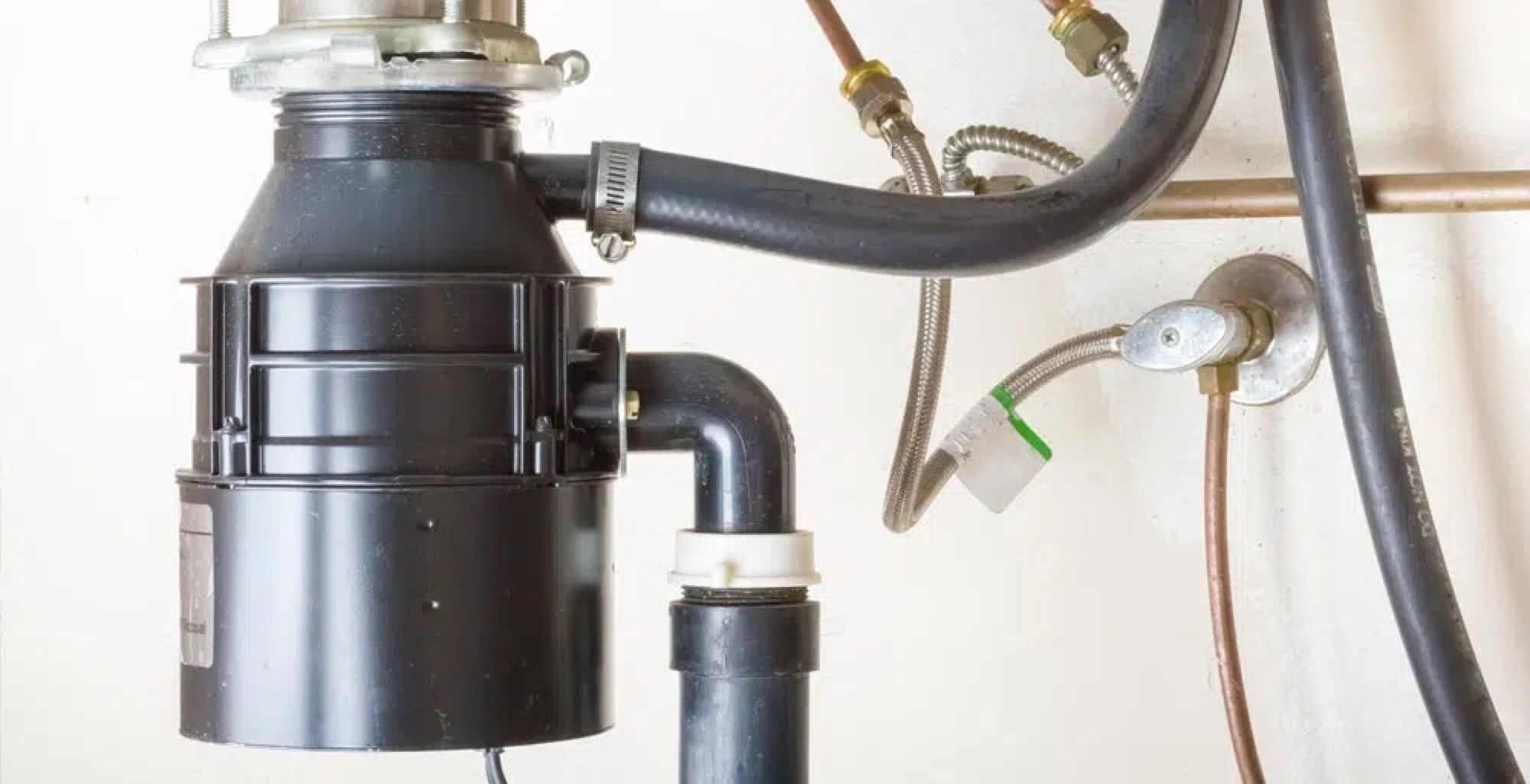Valley Plumbing technician installing a new garbage disposal under a Salt Lake City kitchen sink